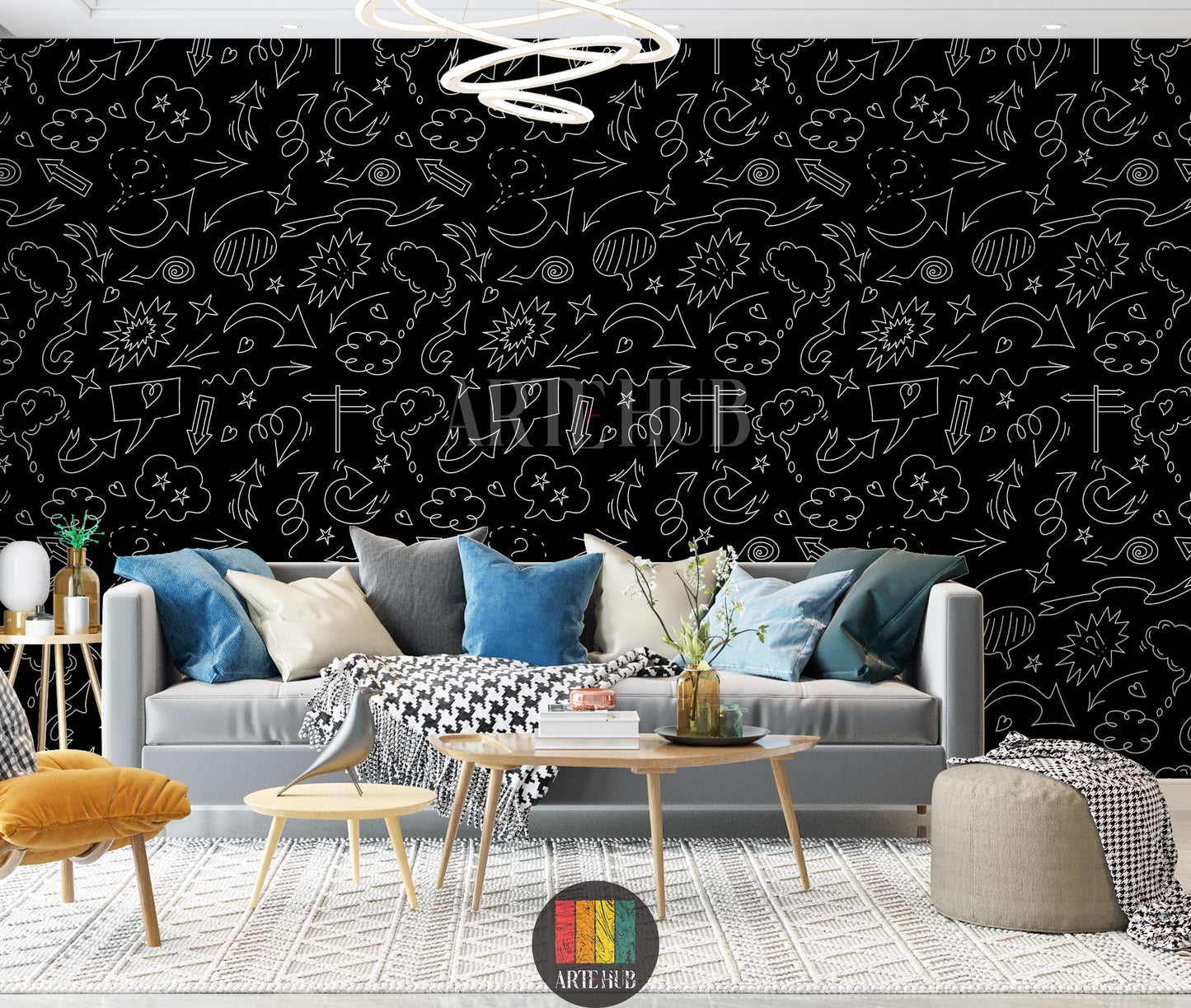 A modern living room features a striking black wallpaper covered in white doodle art, including various arrows, speech bubbles, stars, and clouds. A light grey sofa with blue, grey, and white cushions, a black and white houndstooth throw, a yellow armchair, and wooden tables with decor items are visible. The floor has a textured white rug, creating a vibrant yet sophisticated space.
غرفة معيشة عصرية تتميز بورق حائط أسود لافت للنظر، مزين برسومات شخبطة بيضاء تشمل أسهمًا متنوعة، فقاعات كلام، نجوم، وغيوم. تظهر 