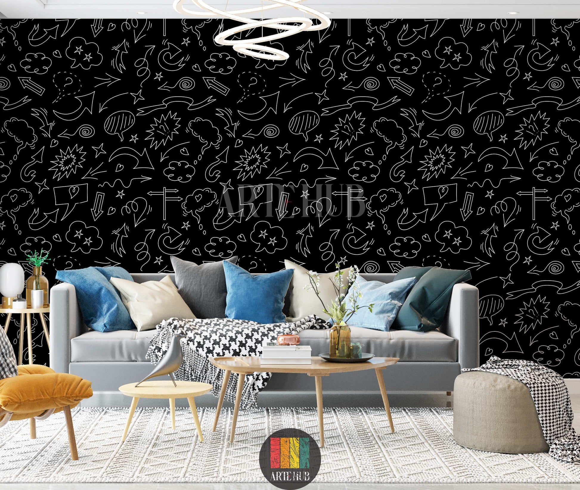 A modern living room features a striking black wallpaper covered in white doodle art, including various arrows, speech bubbles, stars, and clouds. A light grey sofa with blue, grey, and white cushions, a black and white houndstooth throw, a yellow armchair, and wooden tables with decor items are visible. The floor has a textured white rug, creating a vibrant yet sophisticated space.
غرفة معيشة عصرية تتميز بورق حائط أسود لافت للنظر، مزين برسومات شخبطة بيضاء تشمل أسهمًا متنوعة، فقاعات كلام، نجوم، وغيوم. تظهر 
