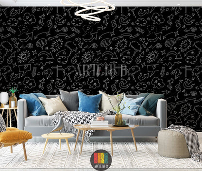 A modern living room features a striking black wallpaper covered in white doodle art, including various arrows, speech bubbles, stars, and clouds. A light grey sofa with blue, grey, and white cushions, a black and white houndstooth throw, a yellow armchair, and wooden tables with decor items are visible. The floor has a textured white rug, creating a vibrant yet sophisticated space.
غرفة معيشة عصرية تتميز بورق حائط أسود لافت للنظر، مزين برسومات شخبطة بيضاء تشمل أسهمًا متنوعة، فقاعات كلام، نجوم، وغيوم. تظهر 