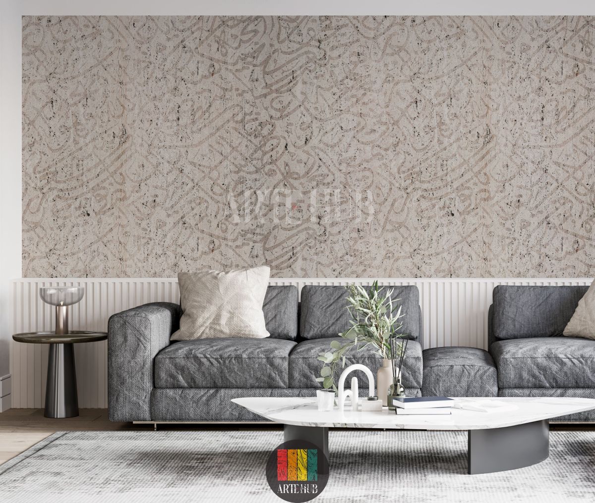 Detailed view of a modern living room wall adorned with light beige textured wallpaper featuring abstract Arabic calligraphy. A stylish grey sofa, a white marble coffee table, and a grey side table complete the contemporary Egyptian interior decor.
منظر تفصيلي لجدار غرفة معيشة عصرية مزين بورق حائط بيج فاتح بنقوش خط عربي تجريدي. تظهر كنبة رمادية أنيقة وطاولة قهوة رخامية بيضاء وطاولة جانبية رمادية لتكمل الديكور الداخلي العصري في مصر.
room: living room