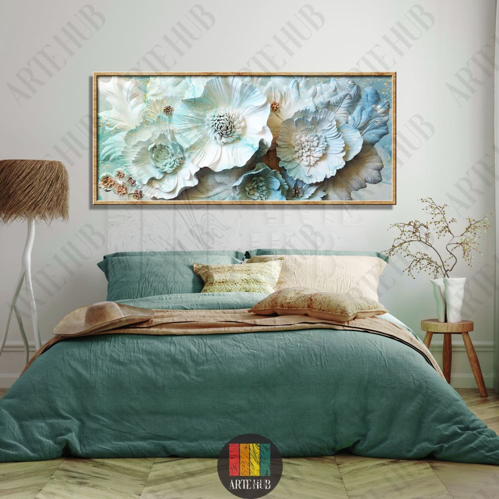 A wide horizontal framed canvas wall art featuring 3D-style light blue and white flowers with subtle gold details hanging above a bed.