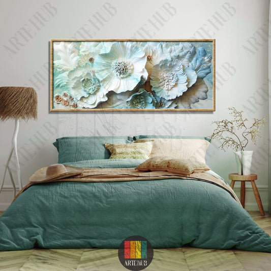 A wide horizontal framed canvas wall art featuring 3D-style light blue and white flowers with subtle gold details hanging above a bed.