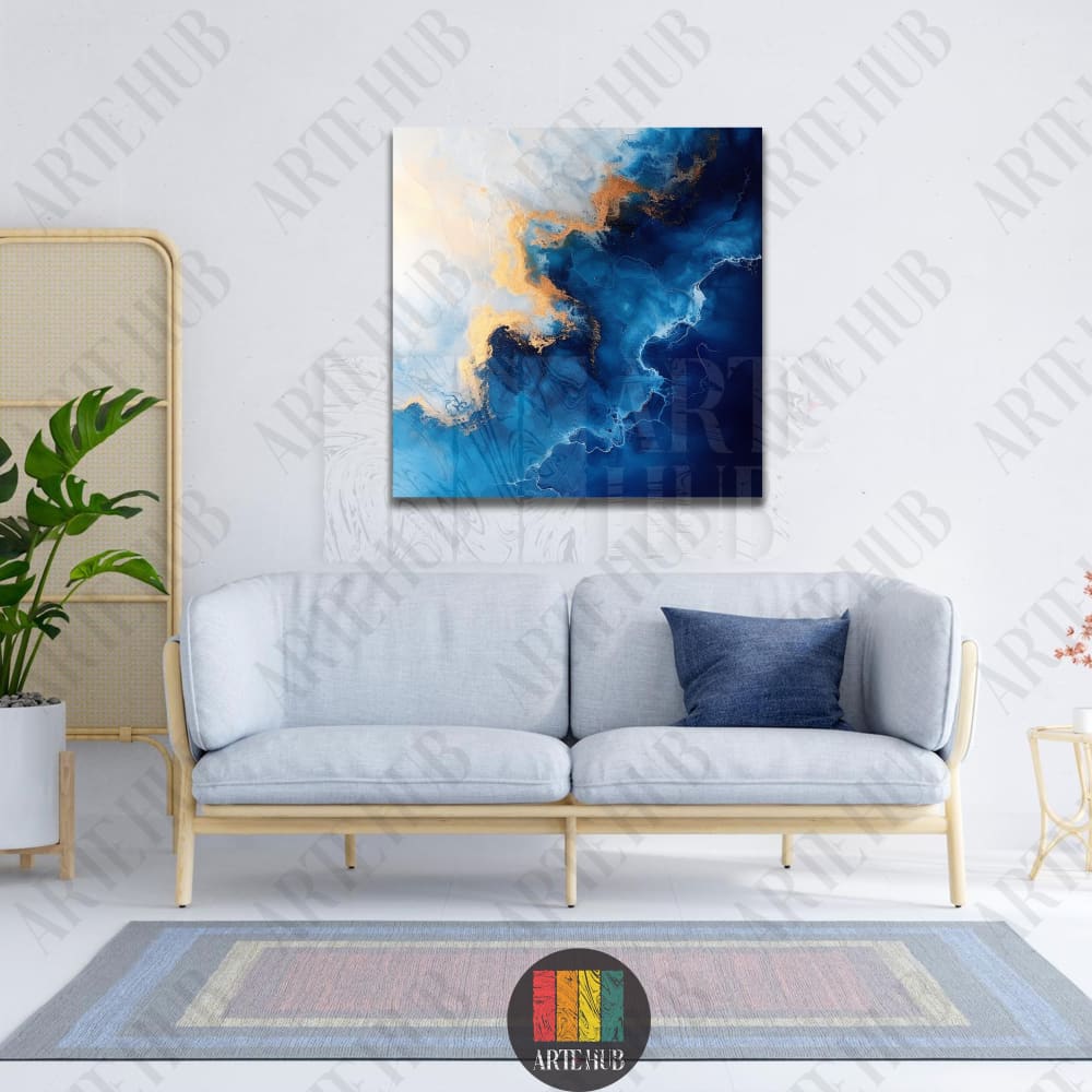 Modern square canvas wall art featuring an abstract fluid ink design in navy blue and shimmering gold marble textures above a grey sofa.