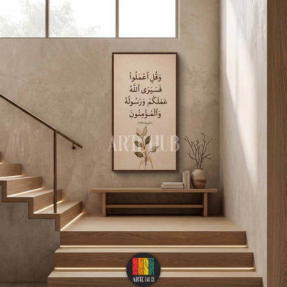 Modern vertical canvas wall art with Arabic calligraphy of Surah At-Tawbah 105 and botanical leaves, hanging in a minimalist wooden staircase interior.