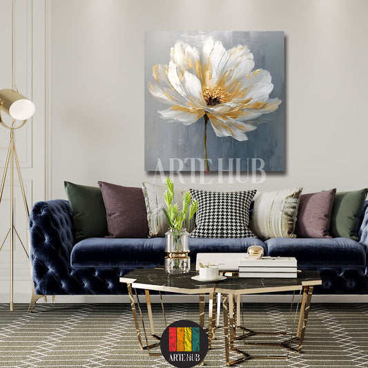 A luxury square canvas wall art piece displaying a stylized white flower with golden highlights on a textured grey background in a modern living room.