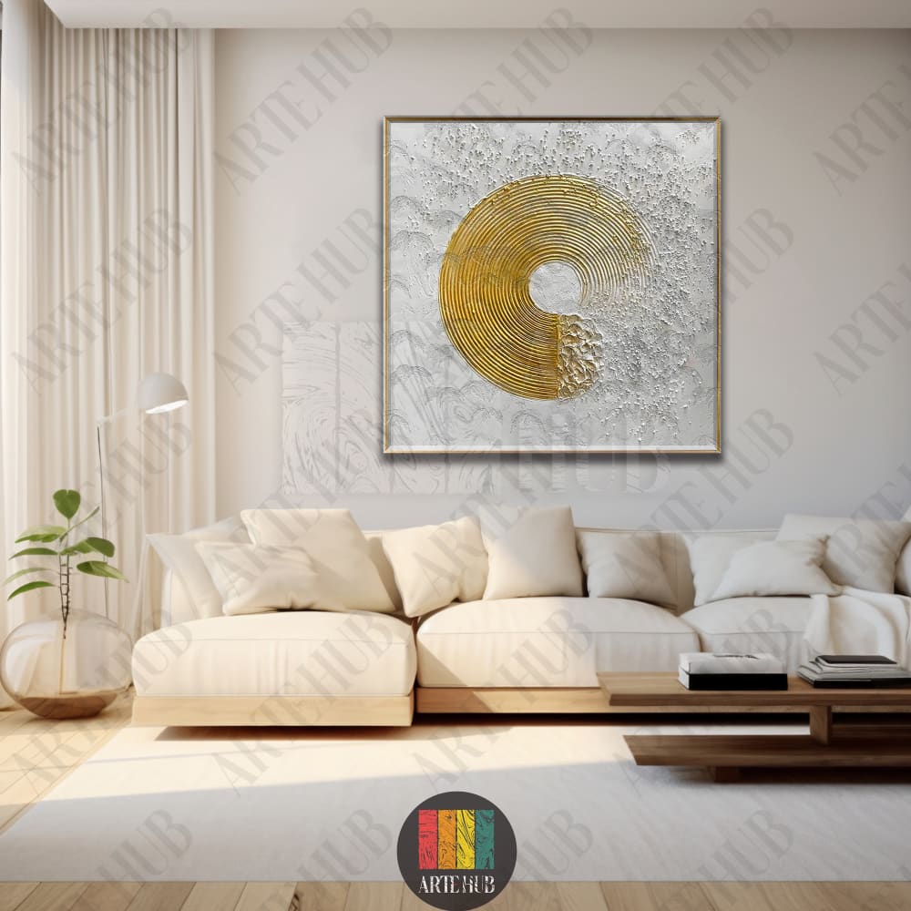 Textured canvas wall art with a golden spiral design and a blue dot, displayed above a cream sofa in a modern home.