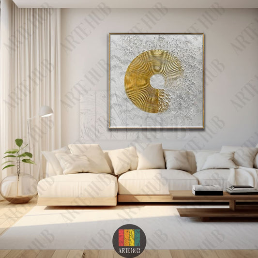 Textured canvas wall art with a golden spiral design and a blue dot, displayed above a cream sofa in a modern home.