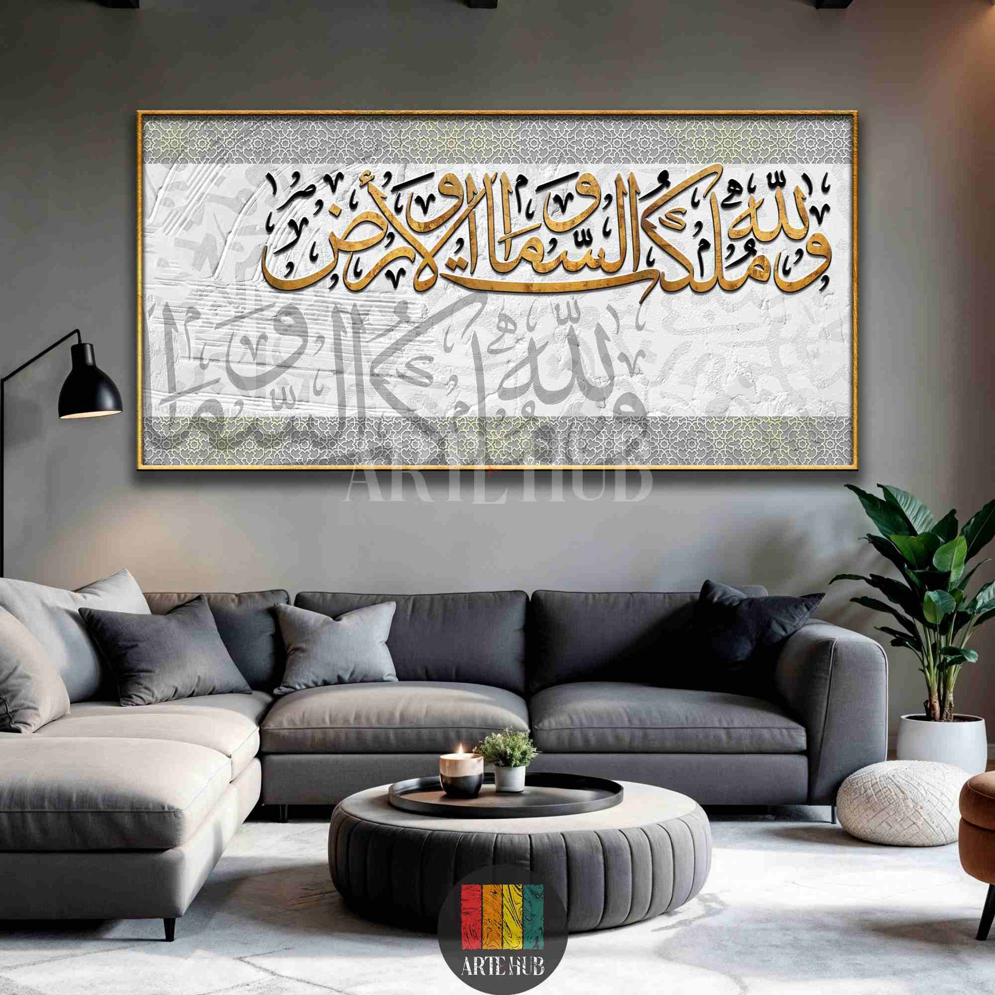 A large horizontal canvas wall art displaying gold Arabic calligraphy on a white and grey textured background, styled in a modern living room.