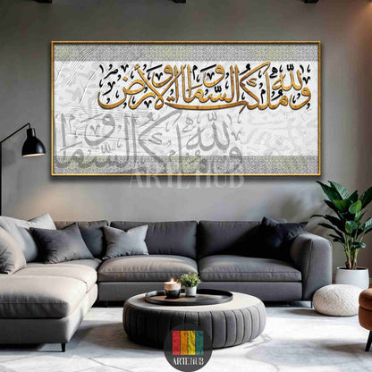A large horizontal canvas wall art displaying gold Arabic calligraphy on a white and grey textured background, styled in a modern living room.